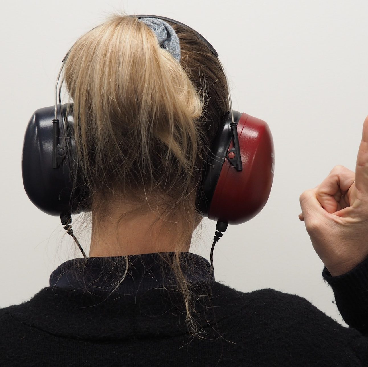 a woman wearing headphones pointing to the side